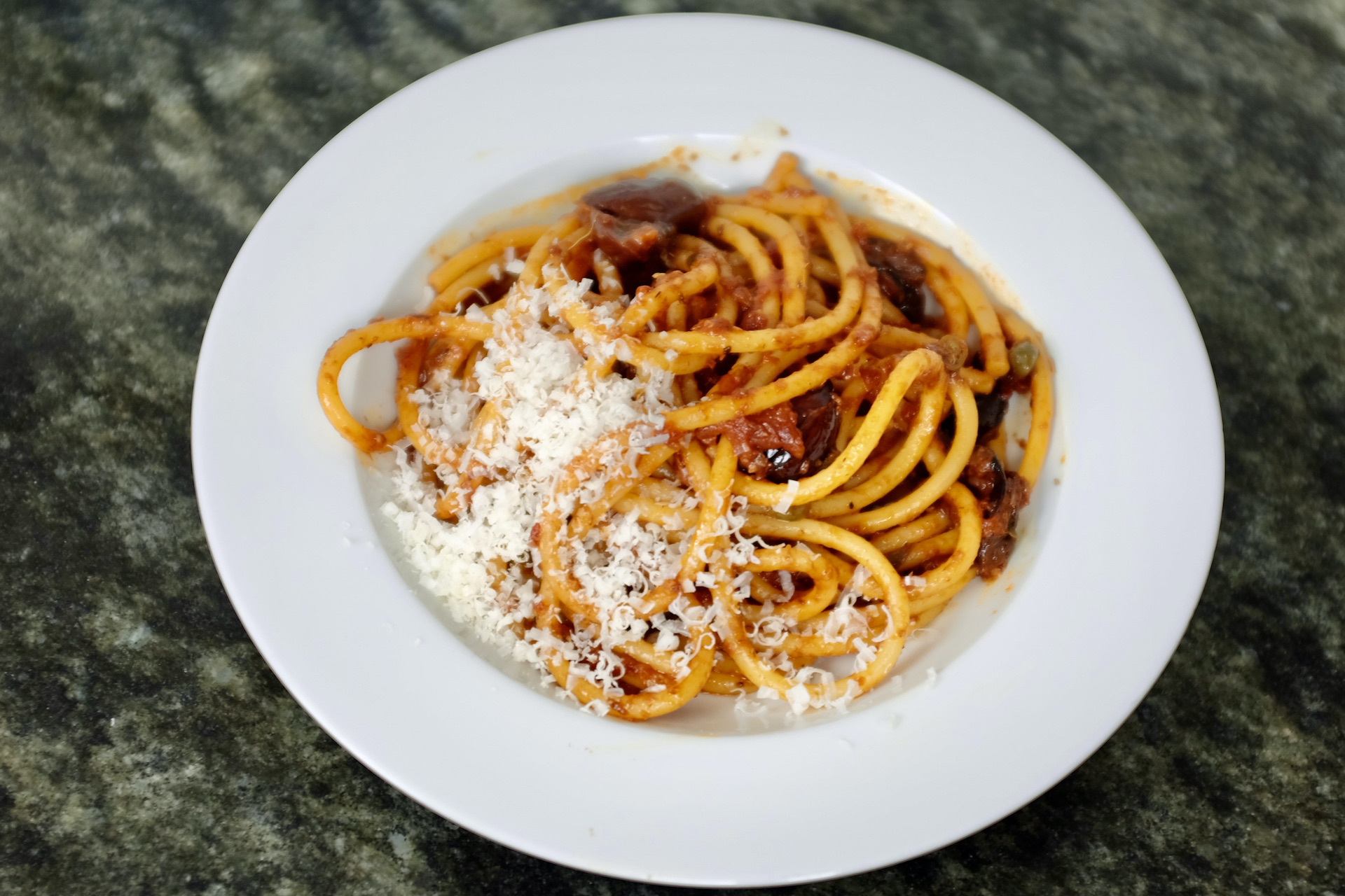 bucatini pasta puttanesca with anchovies capers garlic olives and tomatoes