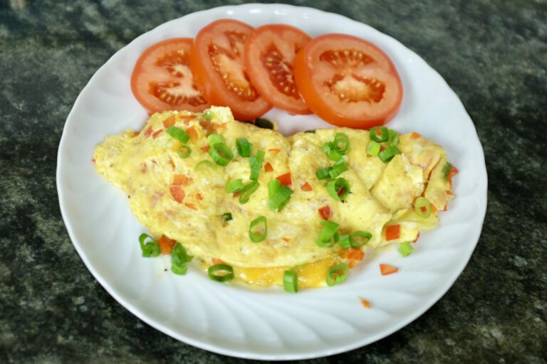 omelette with red bell pepper spring onion and cheddar served with tomato slices