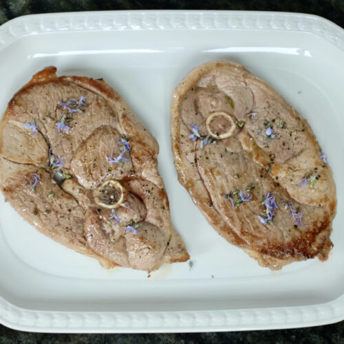 lamb leg steak bone-in fried in fresh rosemary and garlic oil and decorated with rosemary flowers