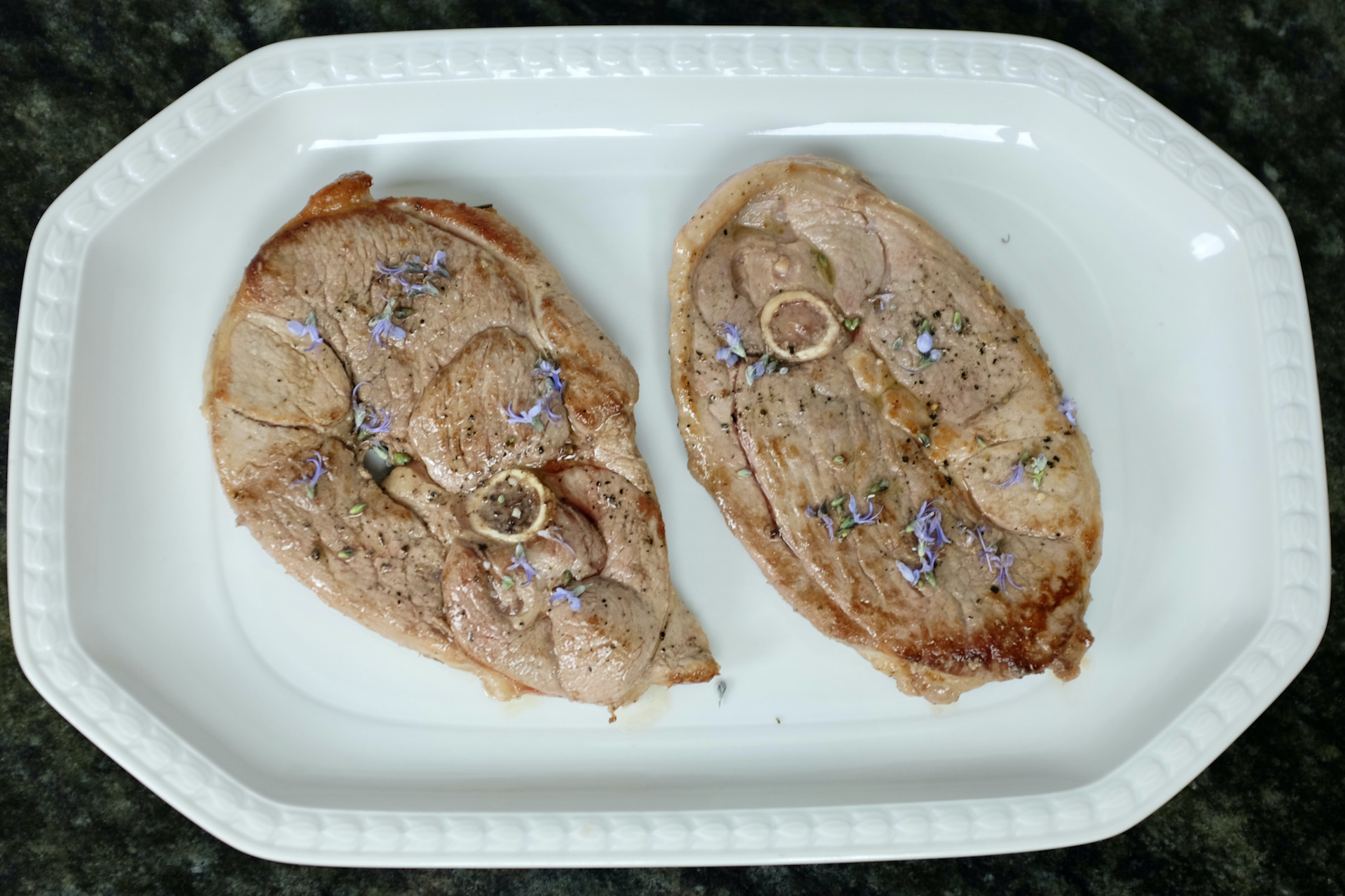 lamb leg steak bone-in fried in fresh rosemary and garlic oil and decorated with rosemary flowers