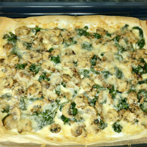 mushroom spinach onion and thyme tart sprinkled with freshly grated gruyère cheese