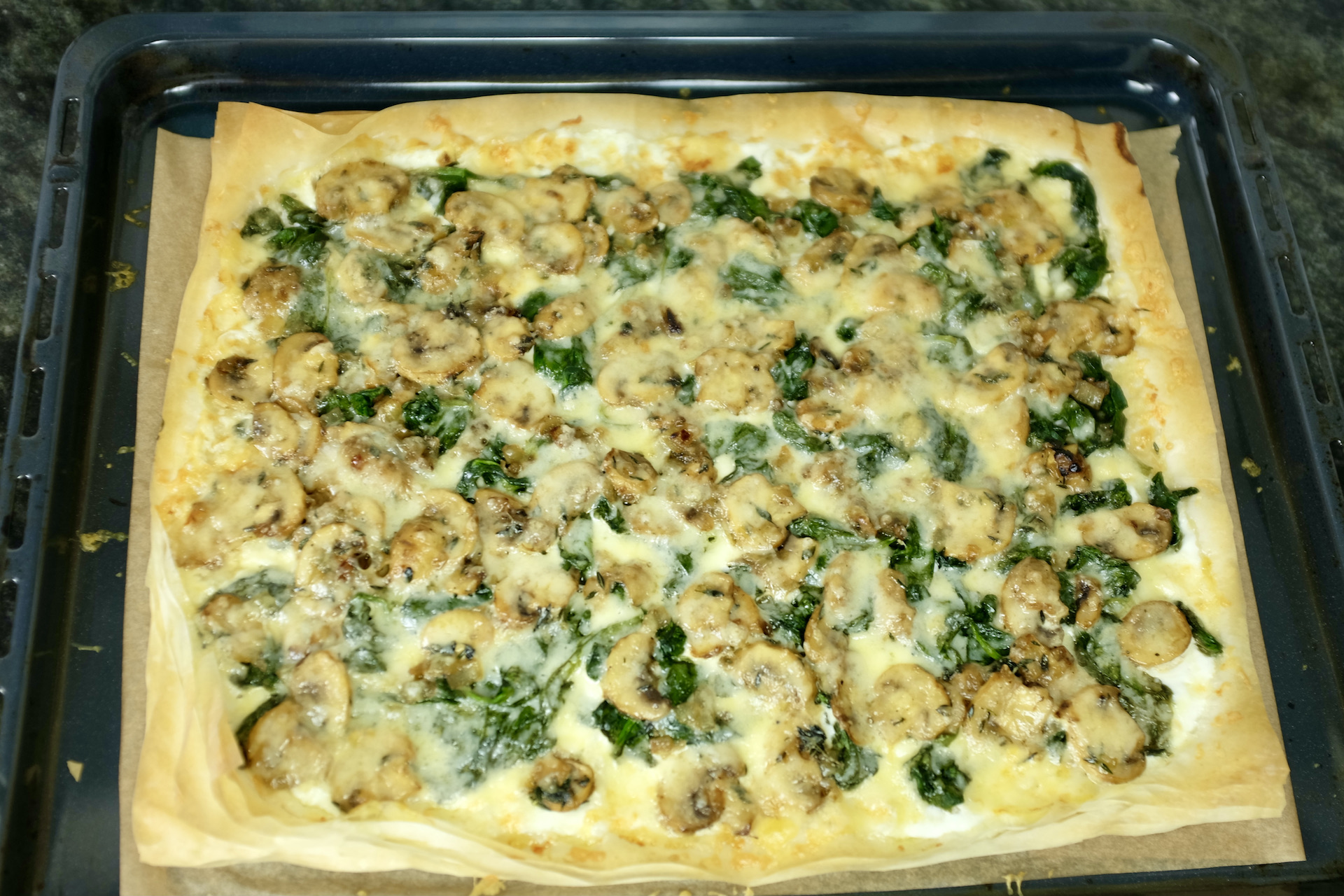 mushroom spinach onion and thyme tart sprinkled with freshly grated gruyère cheese