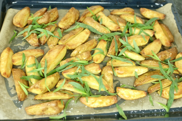 oven baked potato wedges garnished with fresh estragon on top